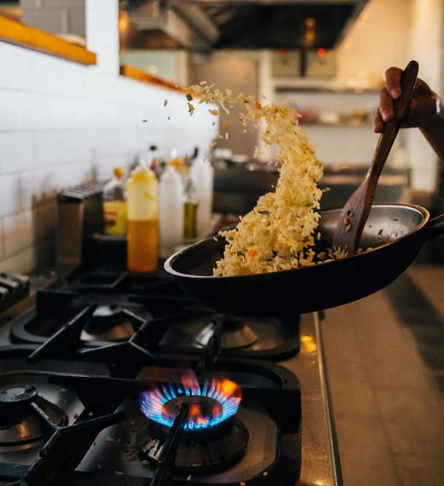 chef cooking rice in a commercial kitchen above an open flame